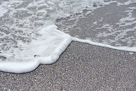 海滩上的海洋泡沫和碎石图片