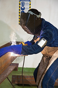 身穿防护服和设备的光束焊接男性劳动者贸易手套职业电焊围裙托梁金属建造图片