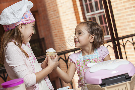 两个小女孩 一起准备蛋糕纸杯蛋糕围裙厨师微笑姐妹厨房乐趣背景图片