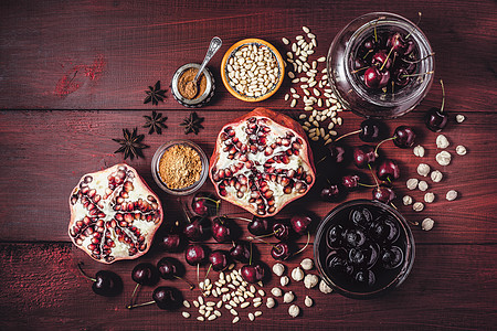 红木桌上的石榴 樱桃和香料仍然在生命中 东方水果的横向概念背景图片