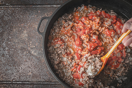 在金属底底的锅里用洋葱和切红番茄粉碎炸肉图片