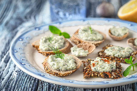 用不同的面包和Tzatziki 放在蓝色桌水平上图片