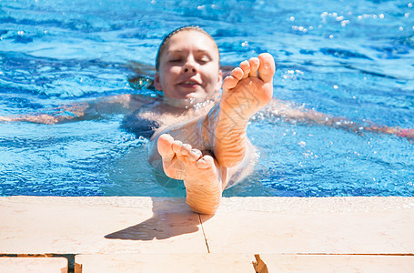 泳池里的年轻女子露出脚来蓝色水池阳光女性摄影女孩们闲暇旅行乐趣脚趾图片