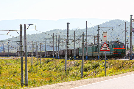 大绿色电动火车头车 汽车通过铁路行驶图片