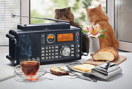 热茶 面包和油 放在桌子上 无线电收音机对着一个开着的窗口午餐窗户营养盘子甜点早餐木头勺子白色黄色图片