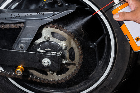 清洁摩托车链和用喷油工具给它浇油服务摩托车运输打扫维修润滑脂男人润滑齿轮车库图片