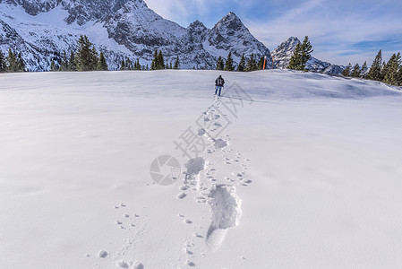 在山峰上走在雪中的人图片