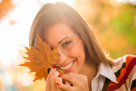 她是个害羞的女孩幸福黄色树叶水平公园微笑森林喜悦叶子享受图片