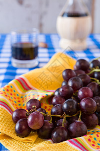 一串红葡萄和一杯红酒的特写桌布餐巾蓝色饮料桌子水果红色白色软木烧瓶图片