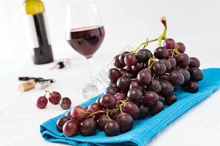 一串红葡萄和一杯红酒的特写水平白色瓶子红色桌子食物软木饮料蓝色水果图片