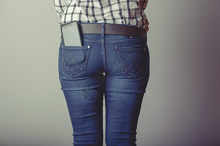 牛仔裤口袋里的智能手机技术屏幕互联网女孩电话商业女性海滩牛仔布图片