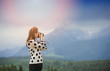 女摄影师在山上拍照片游客女士活动闲暇女孩冒险远足假期背包相机图片