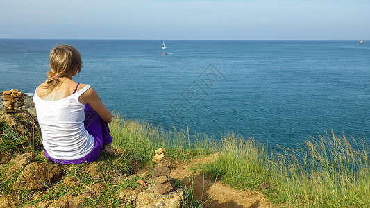 女人享受海洋观景 在海边放松 对地平线进行监视蓝色海滩旅游孩子天空爬坡悬崖男人岩石女孩图片