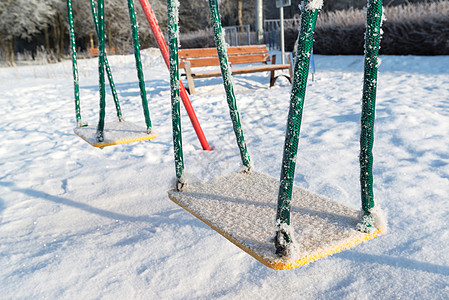 冬季游乐场上雪雪雪覆盖摇摆和滑动冻结孩子们乐趣庭院金属楼梯场景娱乐天气操场背景图片