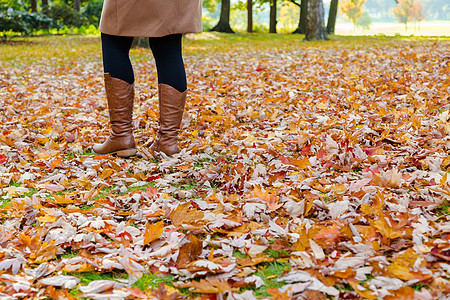 秋季秋天 年轻女子穿着棕皮靴在公园散步图片
