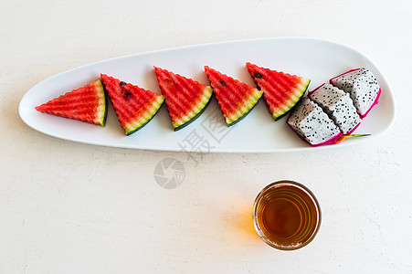 黑龙茶切片西瓜和龙果 在盘子上与热茶背景