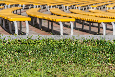 草地背景上一排排整齐的绿色长椅游戏塑料论坛椅子音乐会剧院建筑学民众体育场足球图片