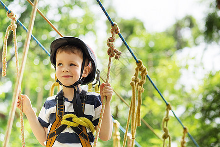 孩子们爬在冒险公园里 男孩喜欢爬绳子绳索头盔游戏耐力力量活动障碍压缩安全危险图片