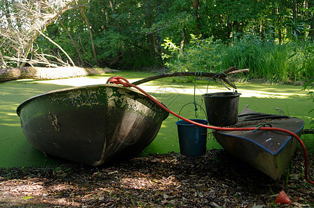 旧独木舟和木船在池塘上岸 上面有水桶图片