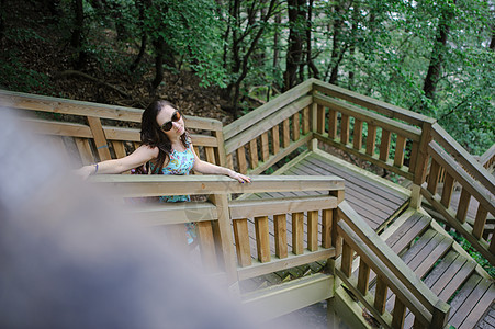 女孩坐在木制楼梯上 在公园里微笑旅行牛仔裤短裤白色头发女士女性假期图片