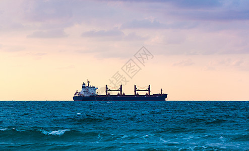 日落背景上漂浮的船舶船运港口天空货物送货波浪载体出口地平线货运图片