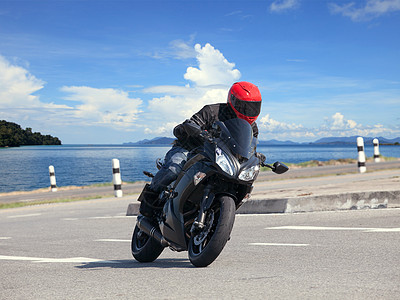 年轻男子骑着大摩托摩托车 与尖锐的灰形曲线相对车轮爱好套装旅行安全领导者速度转弯车辆方法图片