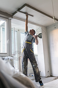 室内墙壁和天花板的粉刷改造 建筑竣工承包商男人涂层工人职业劳动梯子角落工具石膏图片