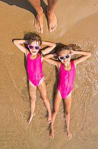两个女孩躺在他背上海沙滩冲浪时 躺着两个女孩 有很多成年成人脚背景图片