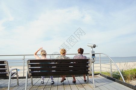 游客坐在沙滩的长椅上海洋支撑蓝色女士海岸海滩阳光旅行天空休息图片