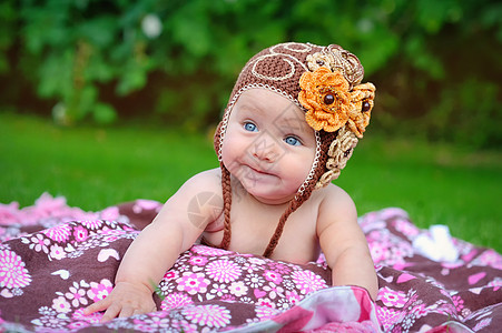 穿着棕色编织帽的可爱婴儿在户外爬行图片