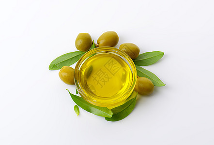 初榨橄榄油橄榄油和绿橄榄液体美食玻璃水果树叶食物盘子背景