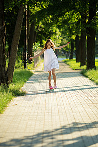 年轻女孩骑着滑板在公园里青少年女士潮人城市生活塑料长板溜冰者裙子城市青年图片