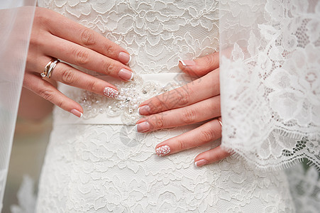 穿着白色裙子的美甲新娘的手 紧贴近身图片
