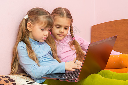 两个女孩在笔记本电脑键盘上推动搜索查询图片