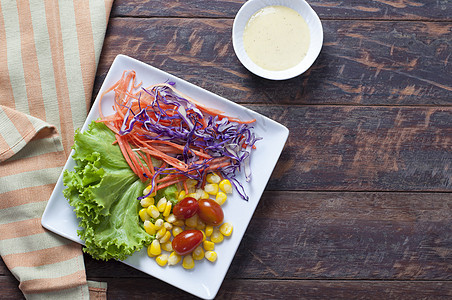 木制桌上的新鲜健康沙拉敷料小吃木头美食蔬菜桌子紫色盘子饮食食物图片