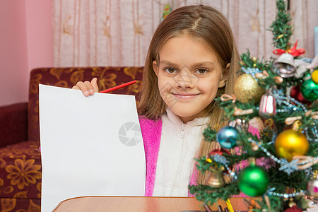欢乐女孩在圣诞节的桌子上 展示一张纸单图片