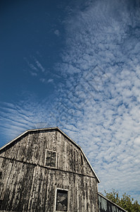 Gambrel屋顶黑漆漆的谷仓 有深蓝色天空和云彩c图片