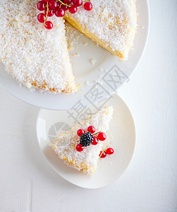白盘上一块自制椰子蛋糕醋栗水果蛋糕椰子薄脆白色食物甜食饮食甜点图片