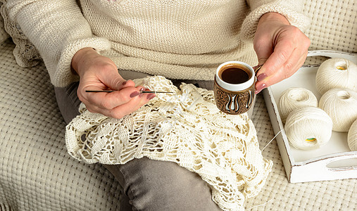 咖啡杯子妇女手织花桌布木头女士针织杯子咖啡黑色棉布托盘手工羊毛背景