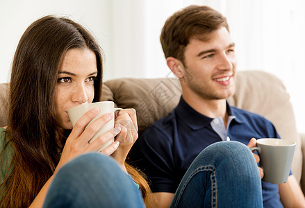 年轻夫妇喝咖啡客厅居住女士电影电视男朋友沙发亲和力家庭娱乐背景图片