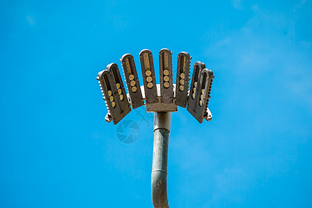 蓝色天空高处的柱子聚光灯白色金属运动灯柱活力街道邮政技术力量灯泡图片
