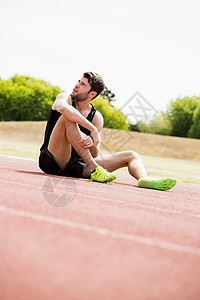 坐在赛马赛道上的累了运动员运动鞋运动服脱水晴天轨道男人挑战男性运动竞赛图片