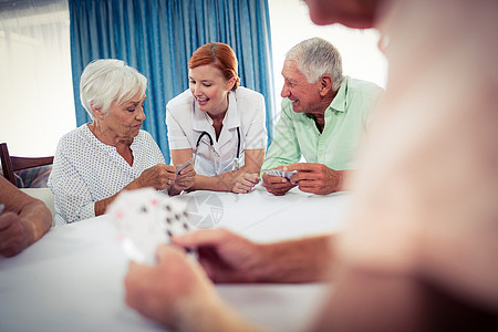 与护士打牌的养恤金领取者流金人员男性女士活动庇护所帮助医疗保健老年背景图片