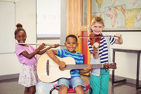 微笑的孩子在课堂上弹吉他 小提琴 长笛图片