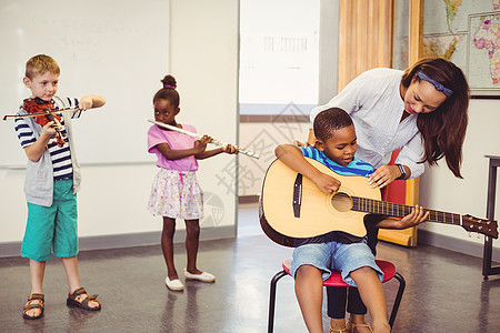 教师协助儿童在课堂上演奏音乐乐器的助教图片