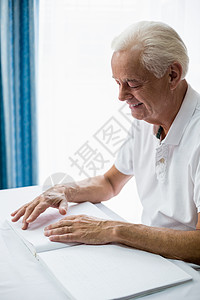 高年男子使用盲文阅读微笑庇护所老年人闲暇男性医学病人疗养院退休老年病图片