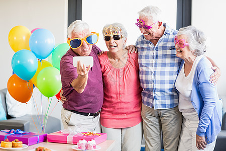 长年老人拿一个带滑稽眼镜的自拍团结医疗保险退休医疗老年病手机男性卫生疗养院老年人图片