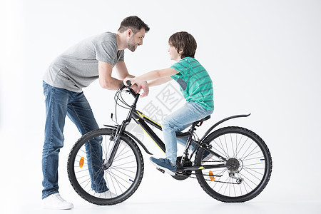 父亲在白色自行车上与儿子交谈的一面微笑成人水平运输背景图片