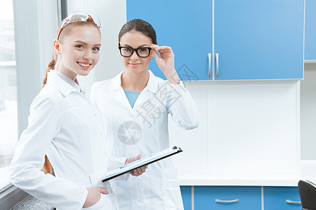 身着白大衣和眼镜的年轻女科学家在实验室镜头中微笑图片