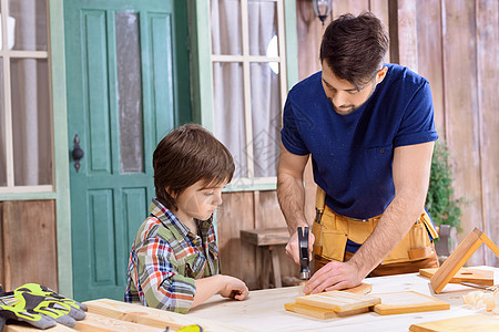 父亲教他如何用木板钉钉钉的画像 教集中的儿子工具工人木工成人童年领班父母作坊爸爸锤子图片
